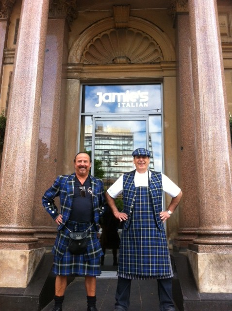 Gennaro Contaldo wearing the Italian National Tartan chef's apron, waistcoat and cap outside Jamie's Italian restaurant in Glasgow with Mike Lem